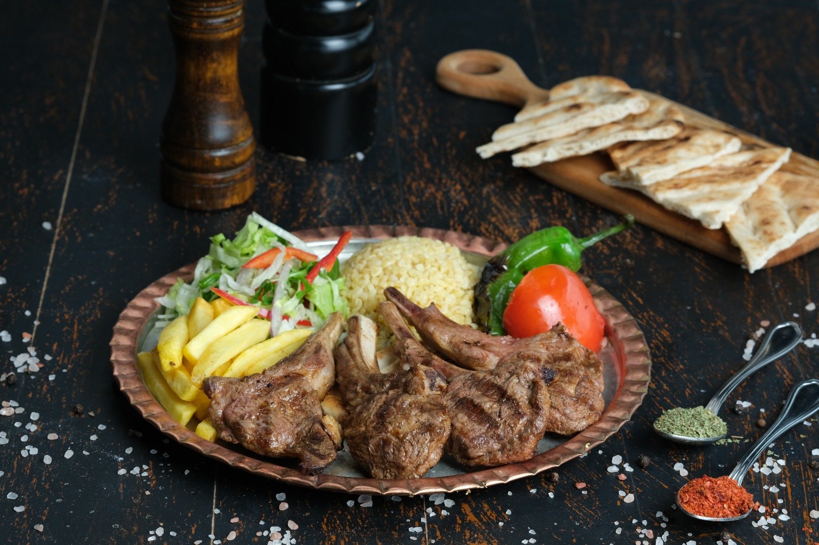 Queb Rooftop - grilled lamb chops with fries, bulgur, salad and grilled pepper on a copper plate