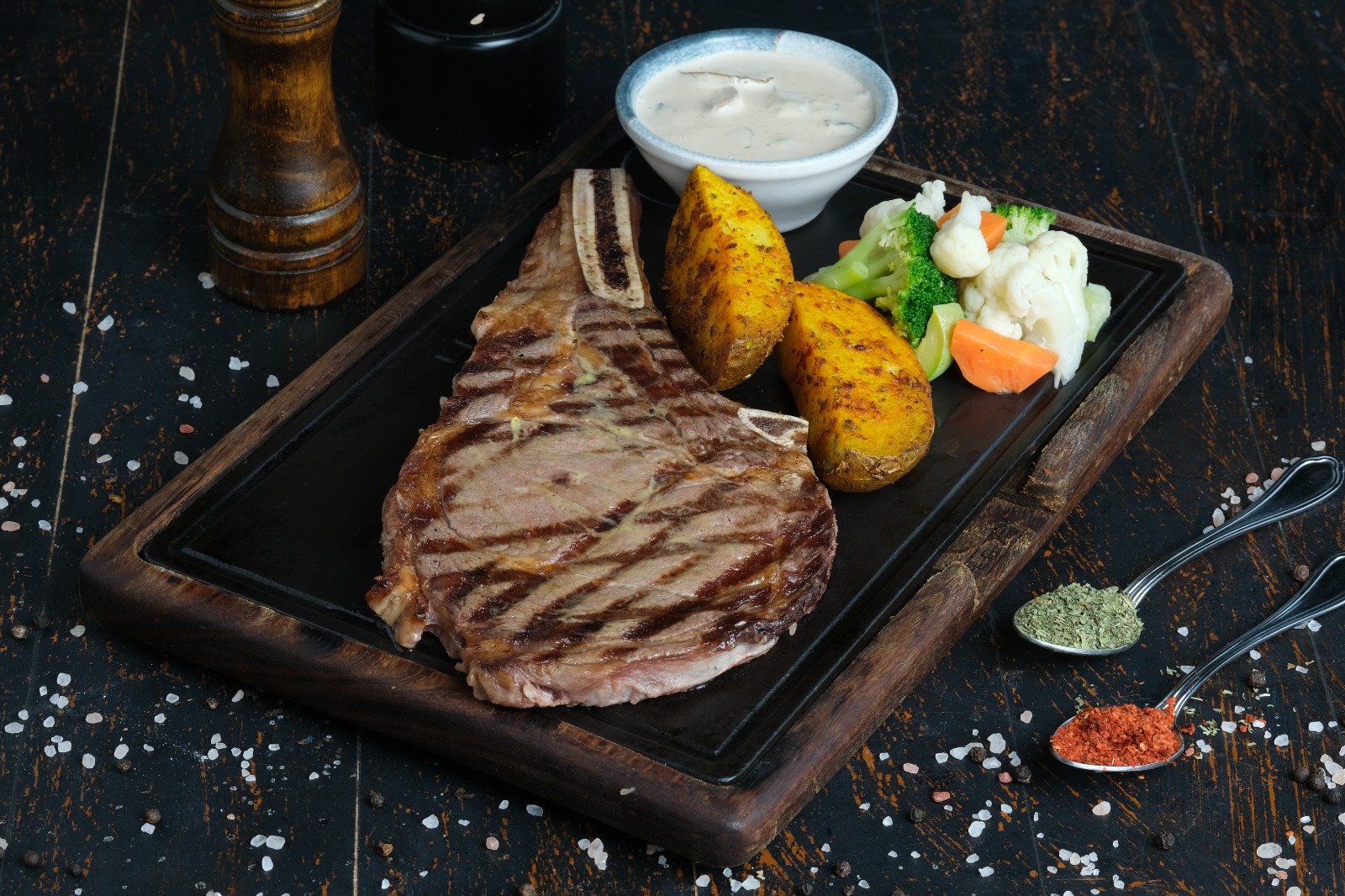 Queb Rooftop - Dallas steak on the bone served on a wooden board with roasted potatoes